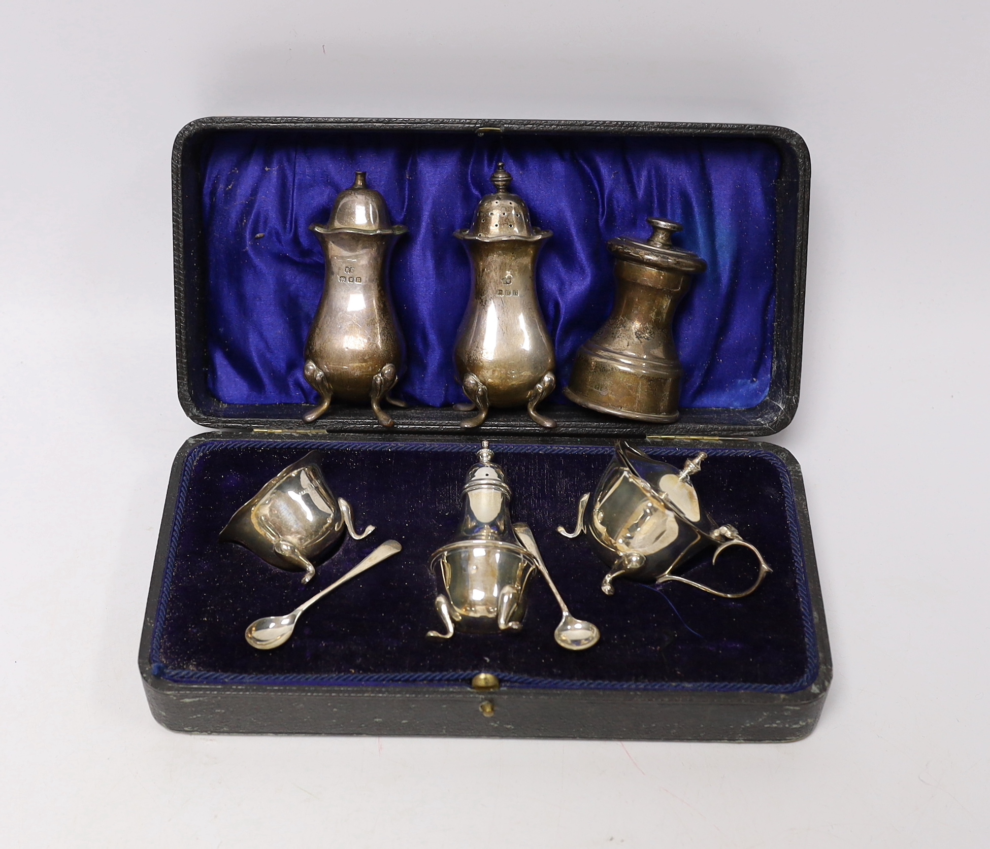 A cased George V silver three piece condiment set, Birmingham, 1919, a pair of later silver pepperettes and a silver mounted pepper mill.